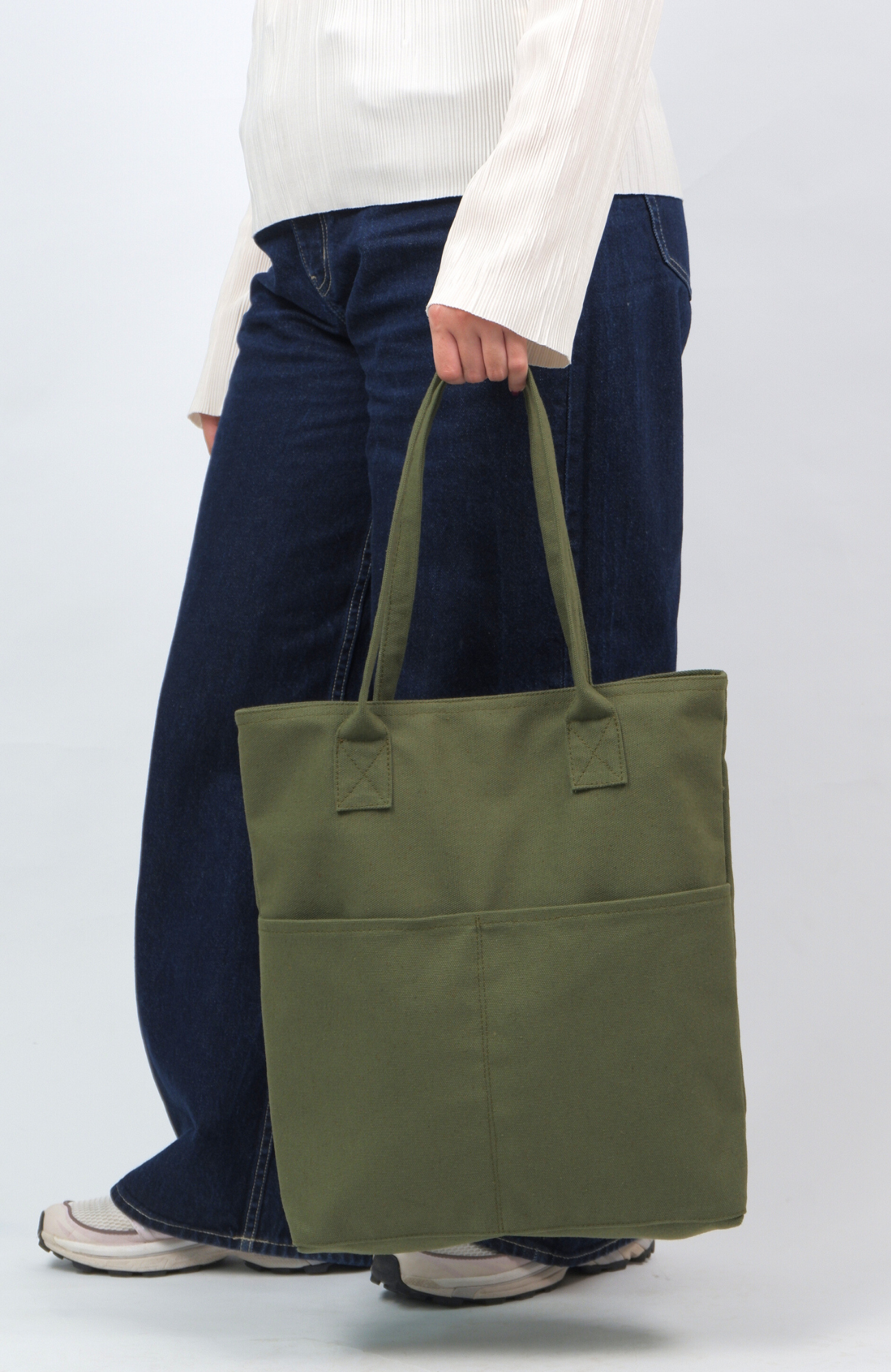 Person holding a green tote bag against a white background